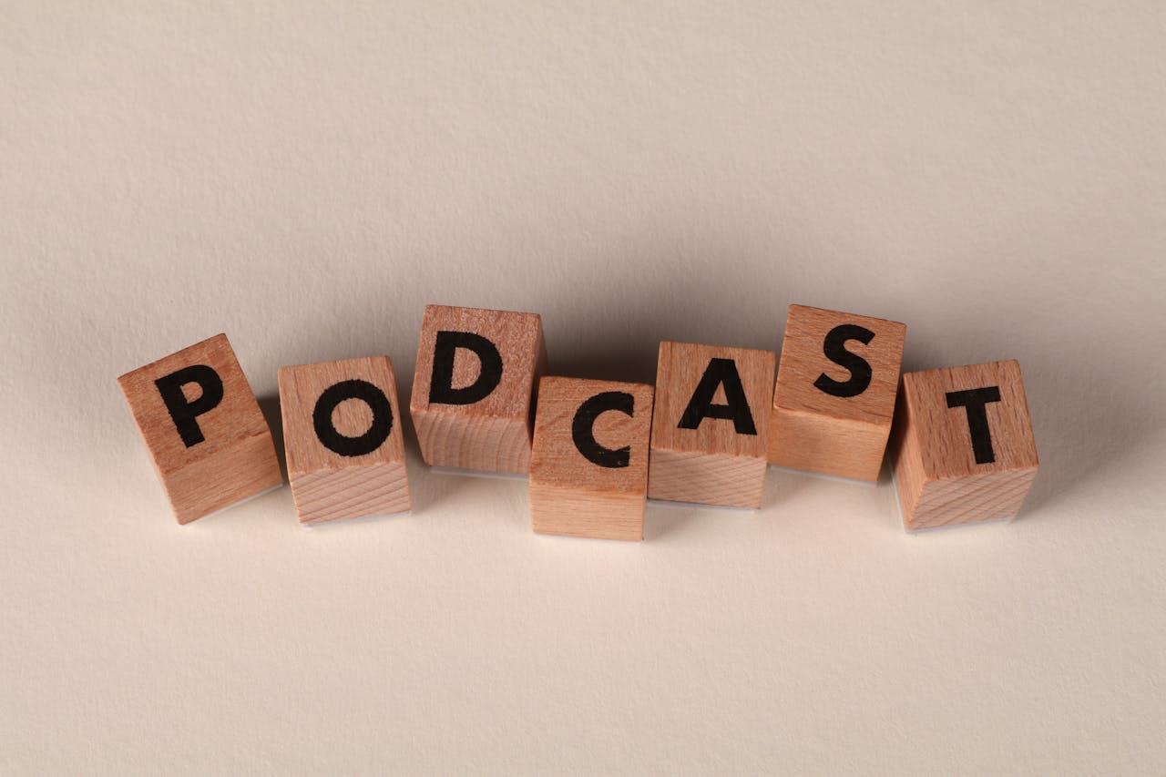 Wooden blocks spelling PODCAST on a neutral background, symbolizing audio content creation.